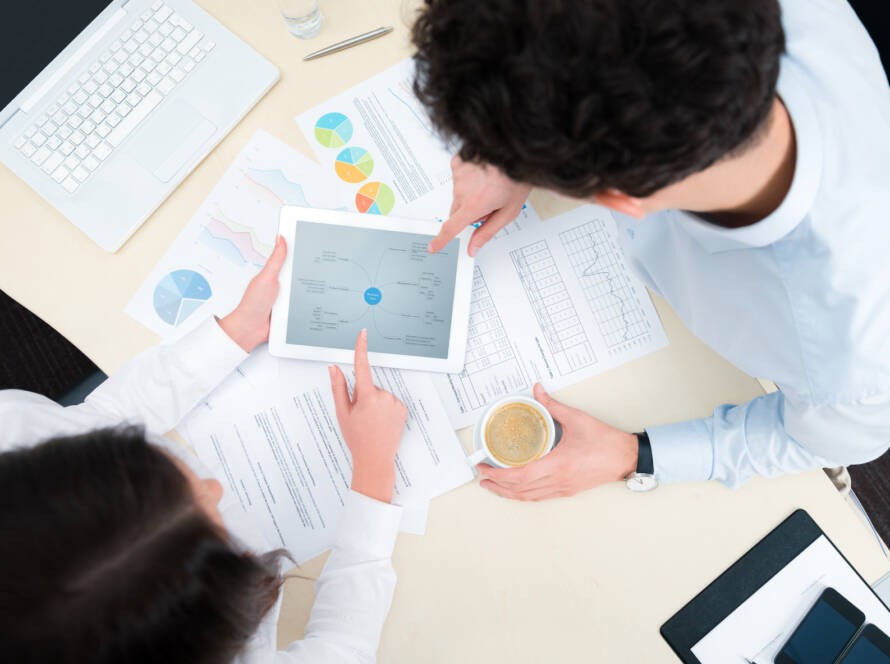 Business team working on a new business plan with modern digital computer. Top view shot.